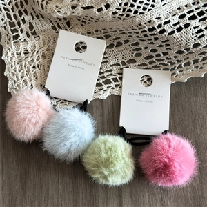 Set di quattro elastici per capelli con pompon colorati su carta da esposizione