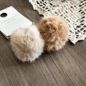 Dettaglio di morbidi pompon di peluche beige e marrone su un piano in legno retro