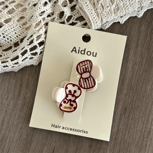 Close-up of red and white printed acrylic hair clips with lucky text on card
