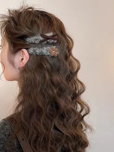 Dettaglio di fermagli per capelli in peluche grigio con fiore e fiocco sui capelli
