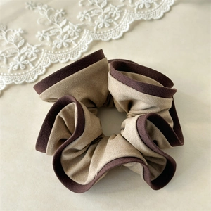Λεπτομερής κοντινή λήψη δίχρωμου πλισέ scrunchie με καφέ άκρη και κομψή διακόσμηση δαντέλας