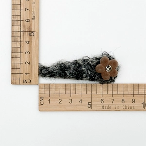 Dettaglio molletta per capelli in peluche grigio con dimensioni su righello in legno