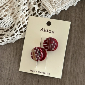 Detail of red acrylic hair clips with polka dots, stripes and lucky girl bow engraving