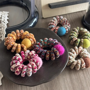 Detailed macro view of colorful knitted telephone wire hair ties with wool felt balls