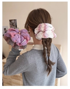 Close-up of soft knitted scrunchies with plush texture and woven brand logo tag