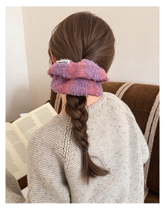 Detail of pink and purple knit scrunchie with brand tag on a casual low ponytail style