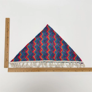 Detailweergave van een kleurrijke gehaakte driehoekige bandana met witte kwastjes en maten
