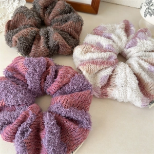Detail showing textures of three knit scrunchies in purple, brown and cream colors