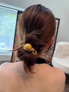 Detail showing high-elasticity colorful pom-pom spiral hair tie on a neat hair bun