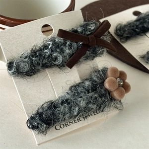 Dettaglio ravvicinato di fermagli per capelli in peluche grigio con fiocco e fiore di strass