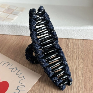 Détail de la pince à cheveux en denim et chaîne dorée sur bloc d'affichage blanc