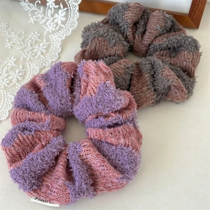Detail showing two knitted stripe scrunchies in purple and grey with soft wool texture