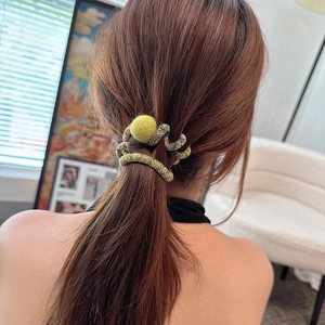 Detail of high-elastic spiral hair tie with a yellow pompom worn on a ponytail