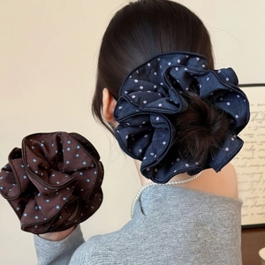 Close-up of oversized satin polka dot scrunchies in navy and brown with a layered design