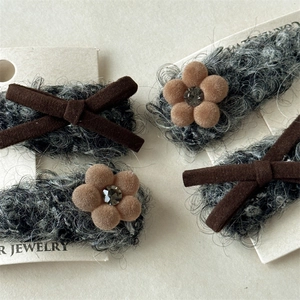 Dettaglio dei fermagli per capelli in peluche grigio con fiori, fiocchi e strass