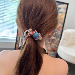 Close-up of a colorful knitted spiral hair tie with blue pom-pom on a ponytail