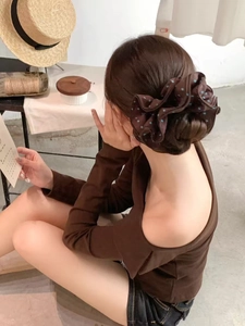 Detailed view of a brown polka dot satin hair scrunchie styled on a bun for women