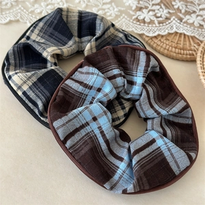 Detail of plaid fabric texture and stitching on two oversized scrunchies in navy and brown