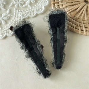 Dettaglio delle clip in metallo nero su fermagli per capelli in finta pelliccia grigia