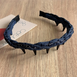 Détail d'un serre-tête en denim tressé avec chaîne argentée et clous punk noirs