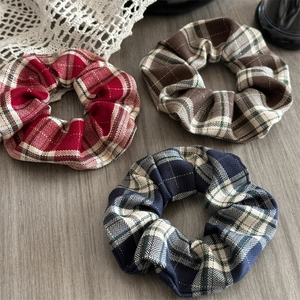 Three-piece set of red plaid scrunchies with elegant gold silk threading on grey wood