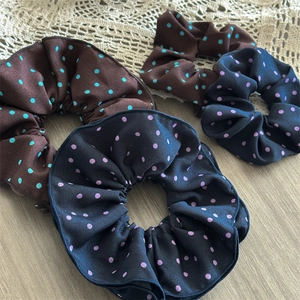 Detail view of four-pack satin polka dot scrunchies with elegant pleats and textures