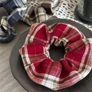 Detail of red plaid scrunchie with gold thread texture on a ceramic tray display