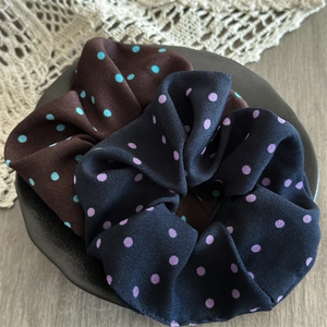 Detail of large satin polka dot scrunchies in brown and navy on a decorative tray