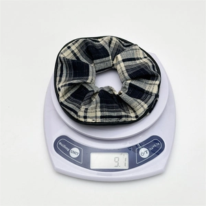 Close-up of a black and white checkered scrunchie weighing 9.1g on a digital scale