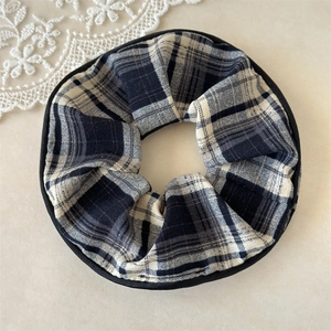 Detailed close-up of a plaid scrunchie with black white grid and fine edge stitching