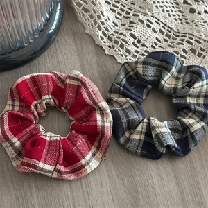 Detail of red and navy plaid scrunchies showing twill fabric texture on wooden background
