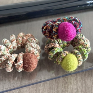 Close-up of spiral hair ties with colorful wool ball accents and plush chenille fabric texture