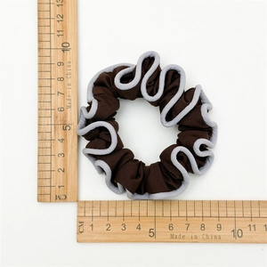 Detail view of a 10cm dark brown scrunchie with grey trim edges and measuring ruler