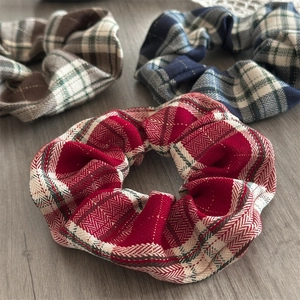 Close-up of three plaid scrunchies with metallic thread in red, blue, and brown patterns