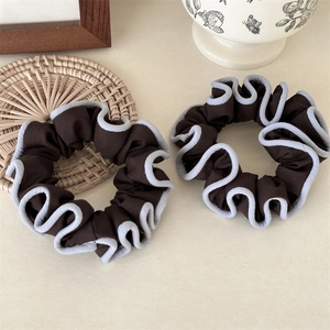 Detailed view of two brown fabric scrunchies with elegant blue scalloped edges