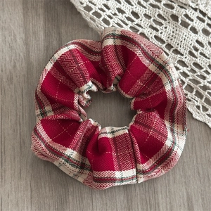 Detailed close-up of red plaid scrunchie with classic herringbone weave fabric texture