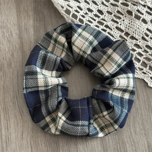 Detail shot of navy and beige herringbone plaid scrunchie on a wooden surface