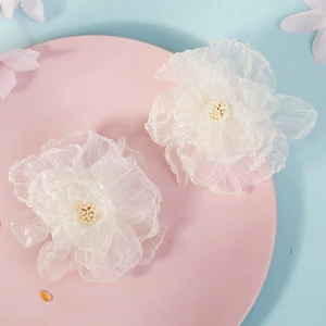 Détail macro de deux barrettes à fleurs en tulle blanc avec étamines délicates
