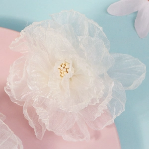 Élégantes pinces à cheveux fleurs en maille blanche sur un présentoir rose et bleu