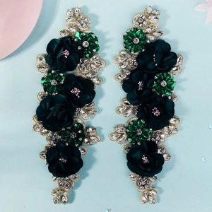 Detailed close-up of handmade 3D floral appliques with emerald rhinestones and gold trim