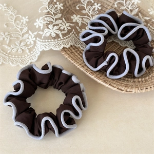 Elegant coffee brown fabric scrunchies with blue contrast trim on a woven tray