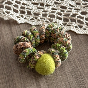 Close-up of spiral hair tie with colorful plush material and vibrant green pompom detail