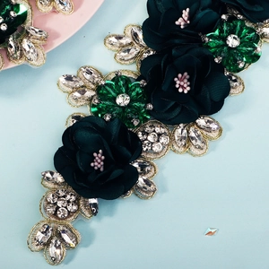 Detailed macro view of green 3D chiffon floral appliqué with emerald rhinestones