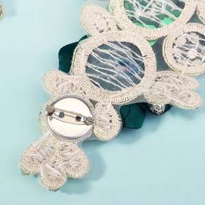 Macro shot of the sturdy metal safety pin and exquisite embroidery on the back of the applique
