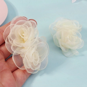 Vue détaillée de pinces à cheveux rose en tulle blanc avec pétales translucides superposés
