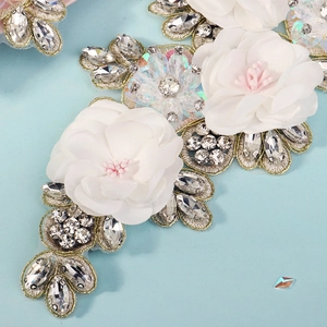 Macro shot of handmade floral applique with sparkling rhinestones and gold embroidery details