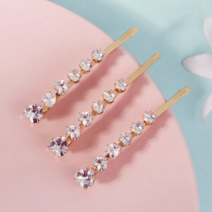 Close-up of three gold-plated hair clips featuring heart-shaped sparkling cubic zirconia