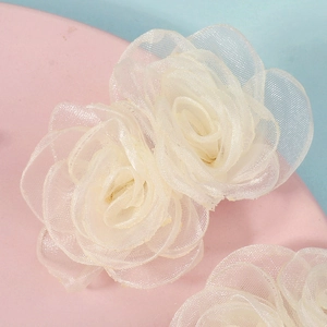 Gros plan de grandes barrettes à fleurs en tulle crème avec pétales de rose multicouches
