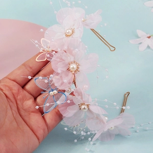 Detail of pink fabric flowers with faux pearls and golden butterfly charms for hair