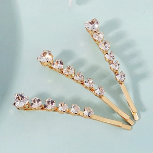Detailed view of three golden hair clips with heart-shaped white zircon stones set in a row